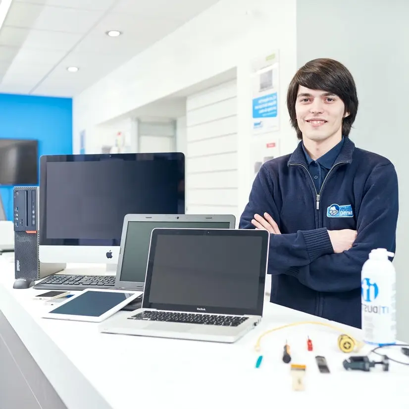 Technicien dépannage informatique avec plusieurs appareils en réparation, incluant ordinateurs portables, PC, tablettes à Béziers.